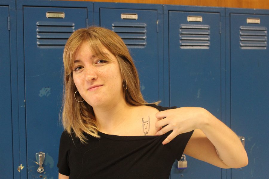 Senior Oona Moorhead shows her tattoo of a devil on her left shoulder. The devil was her fourth tattoo. My aunt is an artist, and when she was in grad school she used to draw all these devils all the time, so when I was a little kid I just had all these devils everywhere,” Moorhead said. “I really liked it, so I got one of those.” Photo by Charlie Holden.
