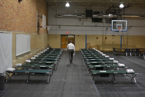 Principal Mike Garrison walks through the rows of green cots that he helped set up. Photo by Dave Winter.