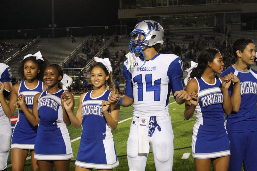 PINKIE PROMISE: Max Perez joins cheerleaders Daejha Taylor, Robyn McCray, Lily Ponce, Lina Coleman, Miles Perkins hold pinkies and sing the school song after the McCallum victory versus Lehman. Photo by Zoe Hutchens.