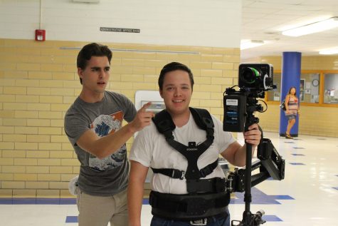 Senior William Magnuson helps junior Noah Powell use a steady cam while filming the Taco Shack Pep Rally. I was spotting him; that means I was making sure he wouldnt fall or walk into something, Magnuson said. Photo by Madison Olsen.