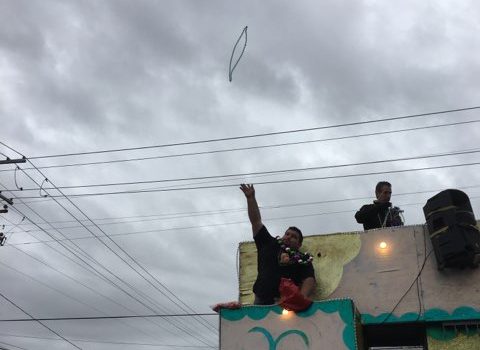 A man throws Mardi Gras beads high in the air into a group of many people who jumped and down excitedly to capture the mans attention. As he threw the beads high in the sky, one person in the crowd said about Mardi Gras: It is just a blast here today everyone comes here in town, and there is never a single sad face here. It is just amazing and get free stuff. Many of the floats resembled party busses and were decorated in gold, purple and green, the Mardi Gras colors. Photo by Jack Hester.