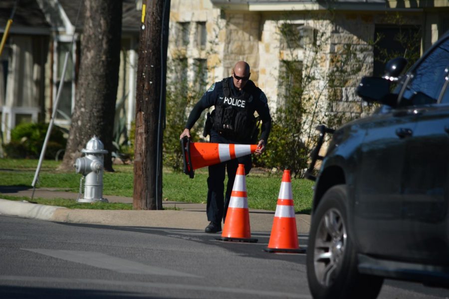 An Austin Police Department officer picks up traffic cones on Tuesday that were used to barricade an area of Houston Street at the Brentwood Townhomes apartment complex after a suspicious package was reported there. The report was a false alarm, and the officers left the scene before the end of fifth period.