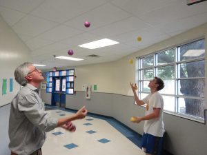 Mr. Pass and rising senior Will Critendon each juggle five balls simultaneously. Critendon and Pass practice their skills out in the math hall as a part of Juggling Club, a weekly club held on Thursdays helping kids learn how and improve their juggling skills. “I’ve been juggling for a couple years now,” Critendon said. “The biggest piece of advice I can give to beginners is just to keep practicing even when it gets frustrating.” Photo by Tomas Marrero.