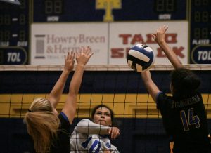 Junior Alexa Fannin spikes the ball between two Anderson defenders during the Knights 3-2 victory over the Trojans at Anderson on Friday night. Fannin, who played for Anderson last year as a sophomore, had eight of the Knights 51 kills for the match. Photo by Bella Russo.