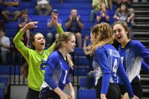 Senior Lindsey Wiley, sophomore Sophia Henderson and junior Liana Smoot celebrate a kill from junior Shaine Rozman.  Photo by Bella Russo.