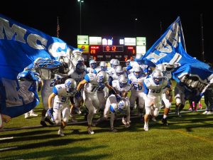 DAWGHOUSE: Varsity football players charge out of the McCallum banner after halftime, leading the Reagan Raiders 28-3. Photo by Gregory James