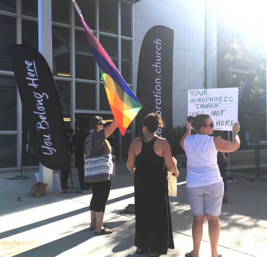 Protesters stand outside the Mueller PAC on Sunday, Sept.  2 during Celebration Church’s service brandishing signs and flags to protest the use of AISD facilities by the Celebration Church. Photo by Jazzabelle Davishines.