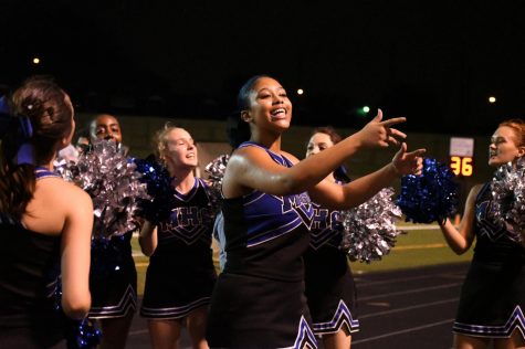 Surrounded by her teammates, Naiya Antar leads the crowd in a cheer at the Mac vs. LBJ game. Although Mac lost the game 41-7 and the team had to cheer through a driving rainstorm, Antar says that she has a good time despite the final score and the wet weather. “To see the crowd going crazy over the football players and then get pumped up when they see us cheer, it’s really fun,” Antar said. Photo by Bella Russo.