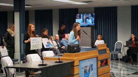 Williams Elementary School teacher Julianne Hart speaks to the board of trustees about her concerns of the lack of security in her school as supporters stand behind her with signs. Williams Elementary doesn’t have proper walls separating the classrooms, enough safe places for students in the case of an emergency, or enough staff to supervise recess safely. Photo by Elisha Scott. 