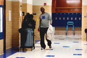 A HARD DAYS KNIGHT: Working hard to keep McCallum clean, janitor Kenneth Sterling takes out the trash from the boys bathroom. After finishing the boys bathroom, he cleaned the science hall. “I never decided to [be a custodian] initially, Sterling said, but once I started doing it I just really liked it, and I still like it today.” Photo by Lily Dashner.