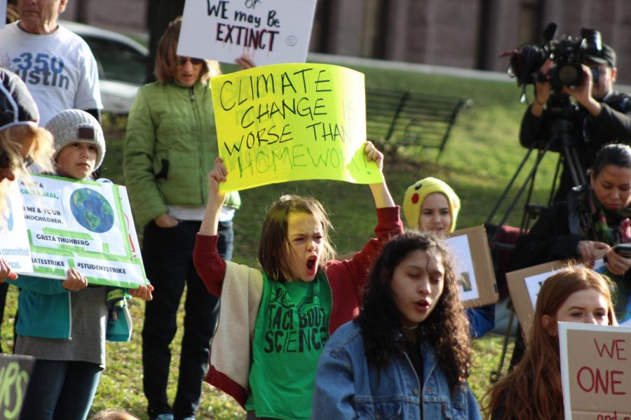 YOUNG AND YELLING: As speaker Morgan [last name] shares his story with the crowd, this young activist cheers and shares his quirky sign comparing school homework to the affects of climate change. 
