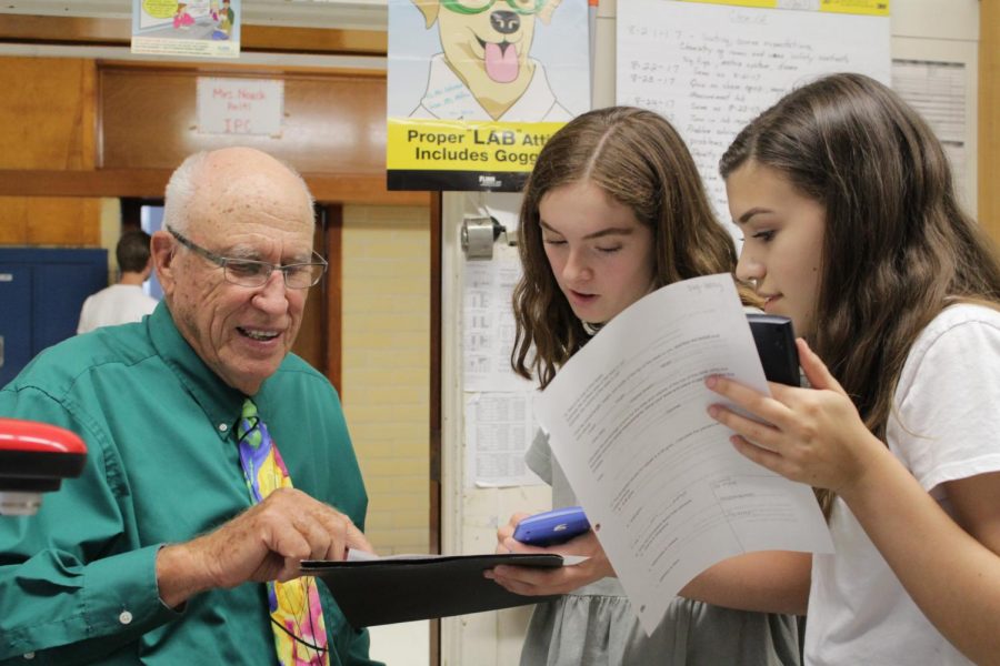 DENSITY IS CALLING: 
Then sophomores, now rising seniors Amelia Paul and Mia Terminella ask chemistry teacher Robert Lehman a question regarding a density lab during their third-period chemistry class on Aug. 23, 2017. The focus of the lab was to explore how sugar and water could portray different levels of density. “We could always count on Mr. Lehman to help us and answer questions,” Paul said. Then junior, now graduate, Lexi Battle, Lehmans classroom aide, demonstrated a density experiment  while the students in the class completed a measurement lab. Battle explained that each colored liquid was denser than the previous color because it contained more sugar and less water. 