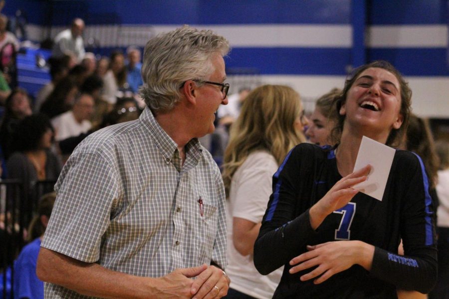 During the pregame ceremony on Teacher Appreciation Night, senior middle hitter Shaine Rozman laughs with math teacher Scott Pass, whom she invited to the game.