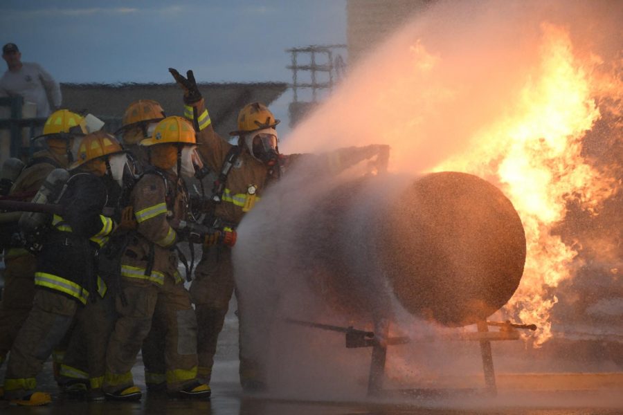 SATURDAY NIGHT’S ALRIGHT FOR FIRE FIGHTING: MAC seniors Ena Nolan and Zach King joined the rest of their LBJ Fire Academy crew in a live propane fire exercise on Saturday Oct. 12 at the Austin Fire Academy. The goal of the practice was for the group of seniors to control the fire enough for a member to get close enough to turn off the tanks gas valve, which would extinguish the flame. Earlier in the day, the juniors in the program, including MAC students Molly Odland, John Hughes, Thomas Lucey, Tex Mitchell and Will Russo, underwent an obstacle course in full gear while trying to conserve air, and stuck around afterwards to watch the seniors and to help replace their air tanks in between rotations. “I don’t even know how to describe it,” Nolan said, who is in her second year in the program. “Watching it [last year] was an ethereal experience, and doing it myself was absolutely amazing, definitely one of the most epic things I’m gonna do in the next couple of years.” Photo by Bella Russo.