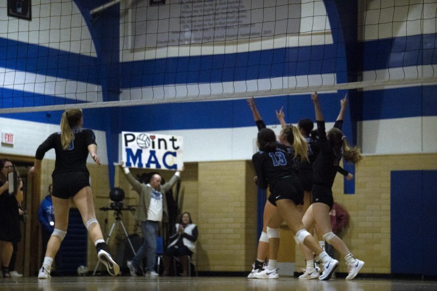 MAKING A POINT: Varsity parent Baron Wilson is ready with the caption in poster form after the Knights win a point during their home loss to Dripping Springs on Oct. 25. “I honestly think that [match] is the best we have ever played, senior middle hitter Shaine Rozman said afterward. We hustled for every single ball and tried to minimize our errors and play well. We could pinpoint drip’s weaknesses and use them to our advantage. We definitely played as a team and I’m super happy with the way we played and glad that I could be a part of it.” Photo by Olive Embry.