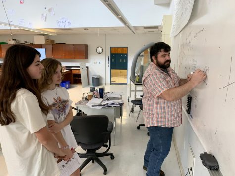 Black and White: Physics teacher Nicholas Koslan draws a free body diagram for juniors Lily Prather and Lily Wilson on his class whiteboard. Koslan, a Physics I and II teacher, previously worked with researchers studying the affects of certain chemicals on brain tumors. Photos by Tomas Marrero