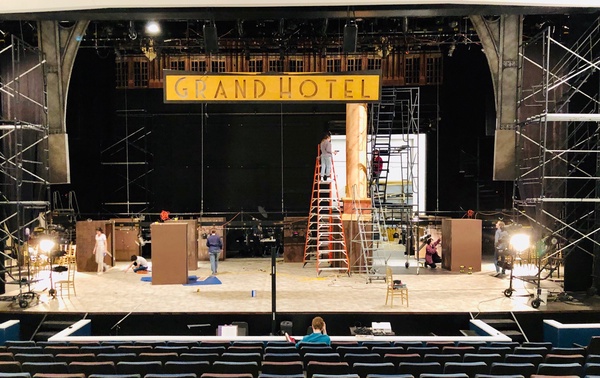 WORK IN PROGRESS: After hanging the Grand Hotel sign, the crew works on assembling the 12 columns that weave throughout the stage. Photo and caption by Ella Rosenblatt.