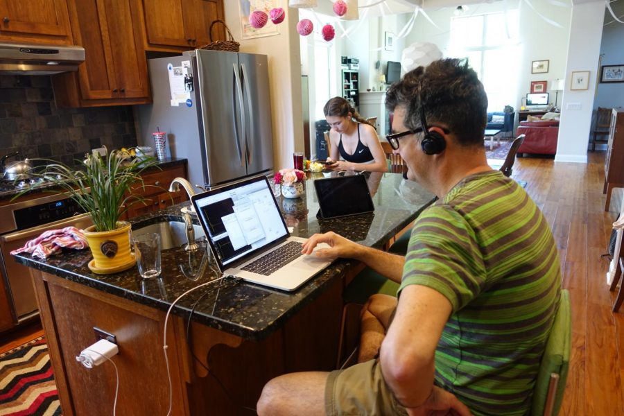 SHARED SPACE: My dad and sister sit at the kitchen counter in our house. My dad works from home a lot, and likes to set up in the kitchen. When hes working, everyone basically goes on with normal life around him. Photo by Lily Wilson.