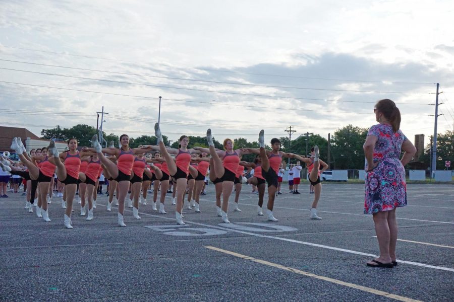 On the morning of the 2019 Taco Shack Bowl,  Blue Brigade Coach Nancy Honeycutt-Searle observes as the McCallum Blue Brigade and Band rehearses its kick routine to “Hey Baby” by Bruce Channell, that they will be performing at the halftime show. Photo by Caleb Melville. 
