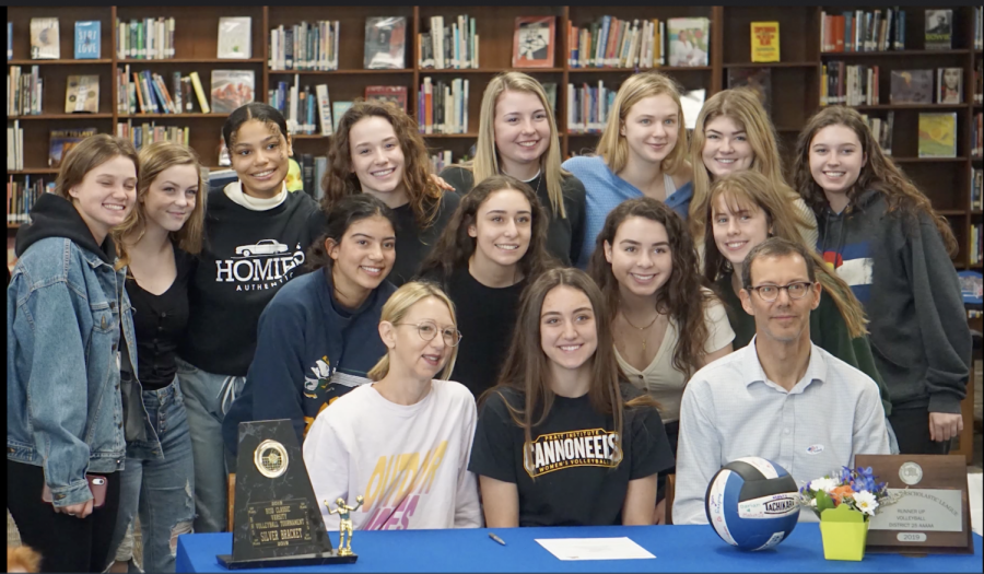 Rozman’s teammates gather for a picture  in the library on Feb. 26 after watching her sign to play for Pratt’s volleyball program. Varsity volleyball coach Amy Brodbeck said that Rozman’s  leadership as a team captain “is admired by not only her coaches but her teammates as well.” Photo by Dave Winter.