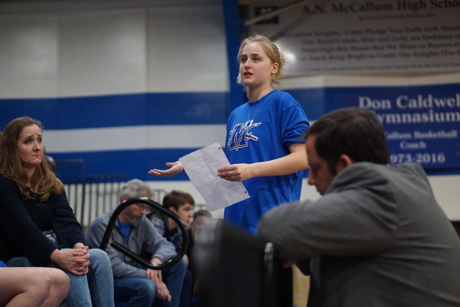 SPEAKING FOR THE TEAM: Girls basketball team captain Ruby Del Valle reads a prepared statement to Austin ISD associate superintendent of high schools Dr. Craig Shapiro at the meeting in the gym. The meeting addressed the recent controversy over the district’s decision to remove the basketball banners from the large gym on Jan. 10. The controversy centered around the hand symbol that a referee makes to indicate that a shot attempt is beyond the 3-point arc. District officials ordered the removal of the banners because of concern that the gesture has more recently been associated with white supremacy. Del Valle acknowledged that the gesture may cause hurt because of its recent “hateful use” toward minority groups but she argued that well-intentioned people should reclaim the symbol’s meaning because it has been used to indicate three points in basketball long before it took on a more sinister meaning.