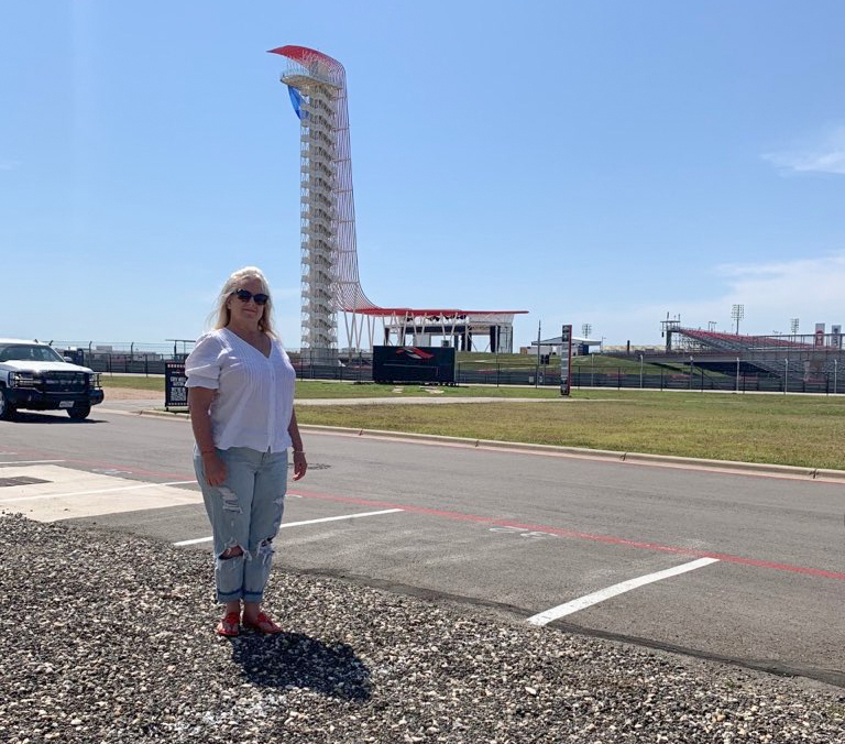 Adamson stands beside the COTA track she drove with her daughter on Mothers Day earlier this year. The only sport I like more than F1 is high school football, Adamson said. I used to just lay on the floor and watch it with my dad. Reporting by Javier Vela. Photo courtesy of Adamson.