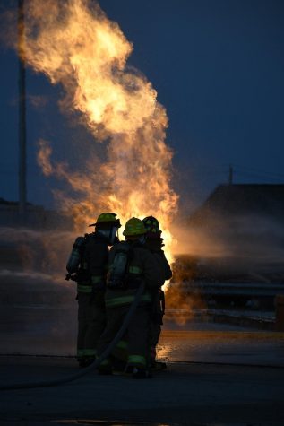 Students from the LBJ Fire Academy work their way towards a propane fire, using fire hoses to control the blaze. The purpose of the drill wasn’t to put out the fire, but to use the spray to get close enough to the propane tank to turn off its fuel source.

Five McCallum seniors, John Hughes, Thomas Lucy, Tex Mitchell, Molly Odland and Will Russo, participated in the live fire skill day, where they put into practice what they’ve learned during the two year student-sharing program at LBJ High School.

“Being in the live fire gave me really intense adrenaline,” senior Molly Odland said. “I was the head of my group, meaning I was in charge of directing the hose line at the fire while my group supported me from behind.”

Senior Will Russo, who also had the chance to lead the group, said that the drill felt like being in a hot car.

“It wasn’t all that scary since you were with a bunch of people, but it was kind of intimidating because there was nothing in between you and the fire but water,” Russo said.

