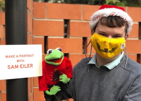Taking a break at a holiday bazaar on Nov. 29, Sam Eiler poses with Kermit as he waits for people to arrive at The Holiday Happening, an outdoor lighting celebration where he was commissioned to draw portraits at the Carpenter Hotel.
