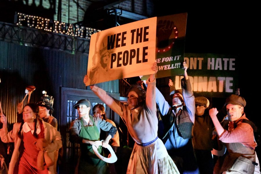 WEE+THE+PEOPLE%3A+Junior+Amethyst+Mellberg-Smith+holds+up+a+sign+during+a+Urinetown+scene+involving+a+protest+for+the+right+to+%E2%80%9Cpee+for+free.%E2%80%9D+Mellberg-Smith+thinks+that+the+show+is+a+commentary+on+the+current+political+climate.+%E2%80%9CIt%E2%80%99s+totally+political+satire%2C%E2%80%9D+Mellberg-Smith+said.+%E2%80%9CIt%E2%80%99s+making+fun+of+serious+situations+that+are+somewhat+similar+to+things+happening+now%2C+but+in+such+a+comedic+and+absurd+way+it+really+shows+how+messy+politics+and+fighting+for+what%E2%80%99s+right+can+be.%E2%80%9D+Mellberg-Smith+said+that+while+being+on+stage+for+the+first+time+in+a+year+was+a+rewarding+experience%2C+her+favorite+part+of+the+production+was+spending+time+with+her+friends.+%E2%80%9CFinally+seeing+people+every+day+made+all+of+the+hard+work+feel+effortless%2C%E2%80%9D+Mellberg-Smith+said%2C+%E2%80%9Cand+I+can%E2%80%99t+wait+to+do+it+again%21%E2%80%9D+Reporting+by+Samantha+Powers.+