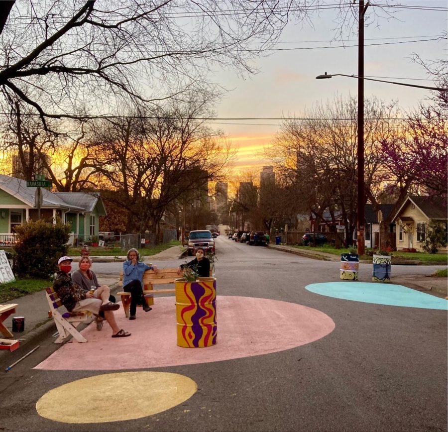 Three neighbors sit on self-painted benches in the street, after a community art event. This moment is an example of place-making to create a more comforting outdoor environment. 