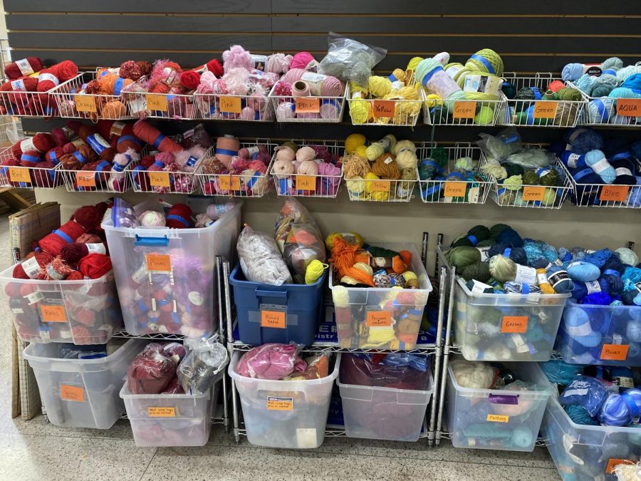 ACR has an extensive yarn collection sorted by color. In this photo you can see part of the yarn section, distributed among a collection of shelves, baskets, and totes.