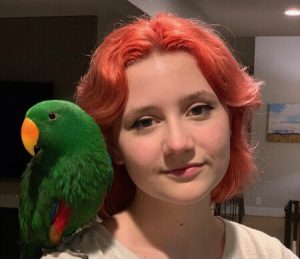 Cinematic arts major Emmylou Stephens stands with her pet eclectus parrot, Sprout. After owning Sprout for the entirety of the COVID-19 pandemic, he has become one of Emmylou’s closest companions.