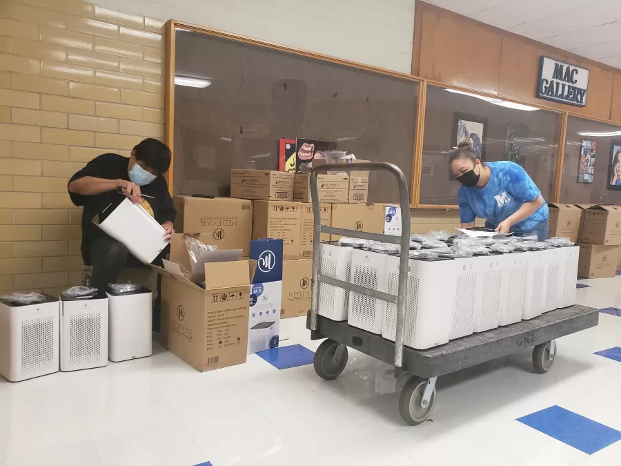 Janitors Daniel Sena and Maria Nunez prepare to distribute air purifiers to every McCallum classroom on Sunday afternoon.