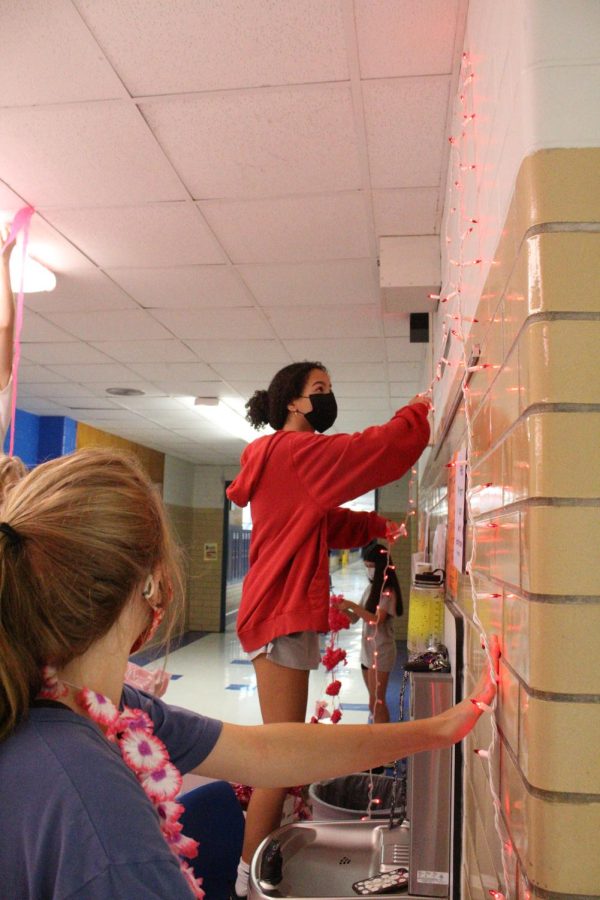 SUNDAY FUNDAY: PALS junior Jolie Gabriel and senior Kendall Smith decorate the school the Sunday before Pink Week in preparation for the week-long fundraiser. The PALS garnished the main corridor with hand-painted posters, pink streamers and lights to set off the festivities for the following week. “This was my first Pink Week as a member of PALS,” senior PAL Anna McClellan said. “Being able to work behind the scenes on decorating the school, as well as planning out events and activities for the whole week was super fun, and something I’m really glad I had the chance to do.” Caption by Naomi Di-Capua.