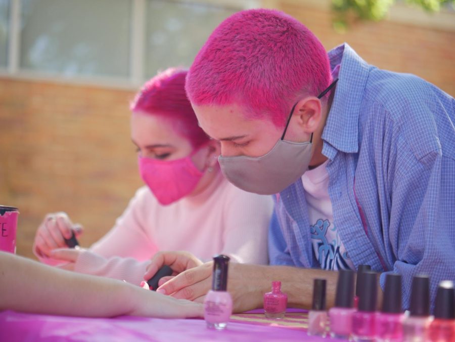 NAILING PINK WEEK ON THE HEAD: The way senior PALs member Gage Sanchez sees Pink Week, it’s not every day that your school turns into a carnival, so you have to make the most of it. “I love how spirited everyone gets,” he said. “It’s such a great atmosphere for everyone to come together and participate in something that raises money for such a great cause.” Monday, Oct. 4 marked the first day of McCallum’s annual Pink Week — an event coordinated by the PALs program under Mr. Cowles. Booths and events, like Monday afternoon’s nail painting and hair styling, are held daily in the courtyard to raise money for the Breast Cancer Resource Center of Austin. This strikes Sanchez as something unique to the McCallum event. “I really love that even though breast cancer may not be relatable for everyone, at Mac we make it to where it’s a fun thing where everyone can enjoy the theme for a whole week,” Sanchez said. Caption by Madelynn Niles.