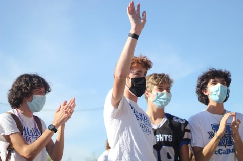 Senior Chris Riley waves to the cheering crowd at the Pink Week pep rally. Despite not racing during the cross country season, Riley has remained a key part of the team. 