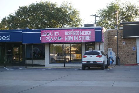 A banner advertising Squid Game-inspired mechandise hangs over a storefront in Northwest Shopping Center on Burnet Road, directly across from Lamar Middle School. According to Reuters, demand for white Vans shoes similar to the ones seen on the show and other related products has increased significantly as Squid Game mania sweeps the nation.