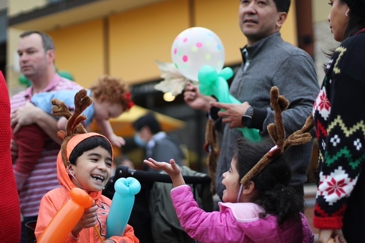 CHEERFUL CROWD: Two kids share a fun time together, as they wait in line for Santa near the large Christmas tree.