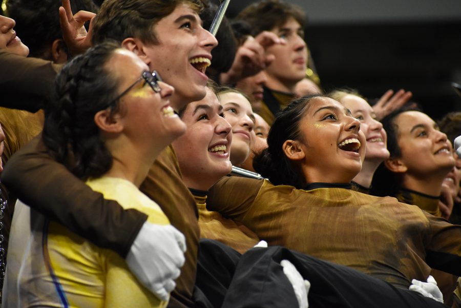 Seniors Natalie Nagy, John Hamlet, Scarlet Frese, sophomore Stella Hufford, junior Stephanie Gallegos, freshman Sadie Swinney and junior Claire De Silva-Yost smile post-show for a group photo at the Alamodome in San Antonio. Photo by Sophie Kessler.