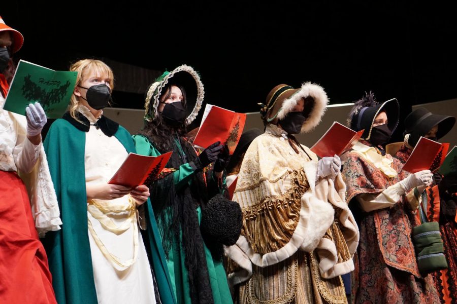 SINGING FOR SCROOGE: To preface the choir concert, a group of choir members sang Christmas carols in a “Dickens-esque” fashion. Senior chamber choralist, Evelyn Griffin (second from the left), told Macjournalsim that the group stuck to classic Christmas songs. “[We sang] 'We Wish You a Merry Christmas,' some Latin thing, 'Silent Night,' that kind of thing,” Griffin said. “My wardrobe situation was a bit stressful, but I enjoy singing with tenors and basses.” Caption by Lucy Marco. 