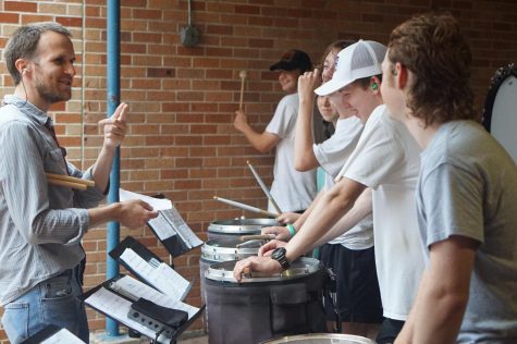 First-year percussion director Scott Lowe enjoys a light moment with the drum line as they rehearsed in the Fine Arts breezeway to avoidthe summer heat and rain on Aug. 5.