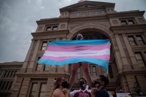 Ali Cross of the Austin Cheer squad waves a trans flag at a rally against anti-trans legislation on April 28, 2021. The Senate passed two bills in 2021 which sought to restrict gender-affirming care, but neither made it out of the House Committee on Public Health. 
Photo by Evan LRoy of The Texas Tribune. Reposted here with the permission of Texas Tribune deputy photo editor John Jordan.
