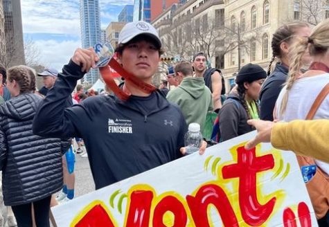 Kenta Asazu celebrates his completion of the full marathon at the Austin Marathon with a medal and a personalized sign. 