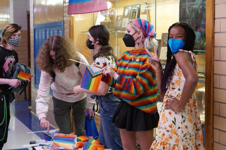 Junior Caytie Brown and senior Ceder Herring, Spectrum members, pass out Pride flags in the hallway on Friday.