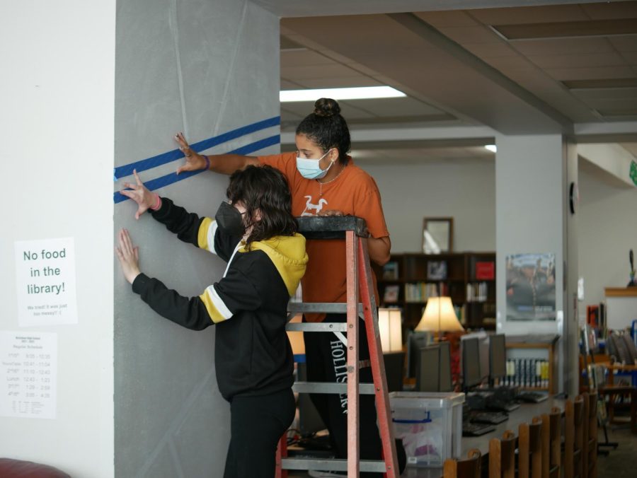 In September of the fall semester, juniors Jillian Hay and 
Regan Sims tape the boundaries of what would become the cartoon character mural inside the library. 