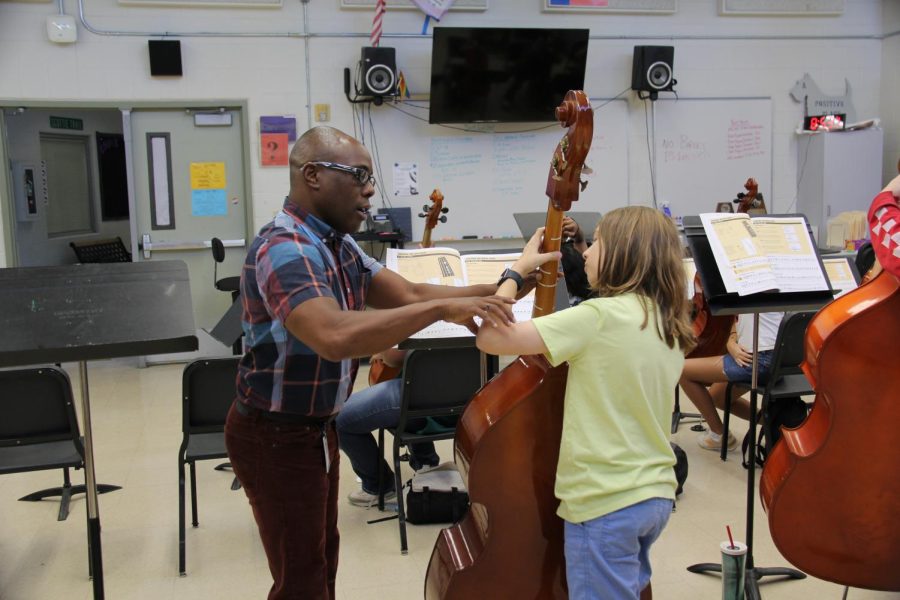 Orchestra director Ricky Pringle helps a sixth grader in the fifth-period beginner cello and bass class at Lamar Middle School learn notes and finger position.