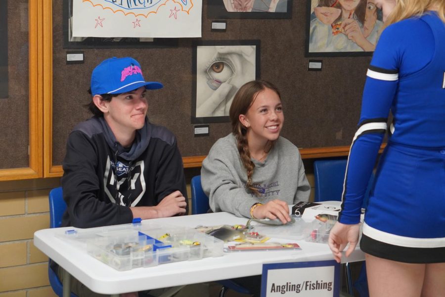 FISHING FRIENDS: Freshmen Sienna Gunning and sophomore Fin Kirsch sit at the Mac Angling Club table, advertising to visitors at "A Knight at McCallum." Gunning decided to join the club at the beginning of this school year to find new ways to experience one of her favorite hobbies.

“I’ve always enjoyed fishing, and I was looking for a club to join,” she said, “so I joined fishing club, [and] it was something different.” 

Even though it’s only her first year as a Knight, Gunning appreciated the opportunity to show off one of the many extracurriculars that McCallum offers, as well as getting to see the future freshmen take a look around campus.

“I enjoyed showing the bait off and just talking to other people about fishing,” she said. “It was nice to see them interested and excited to be apart of Mac fishing club when they come to McCallum.” Caption by Francie Wilhelm. Photo by Dave Winter.