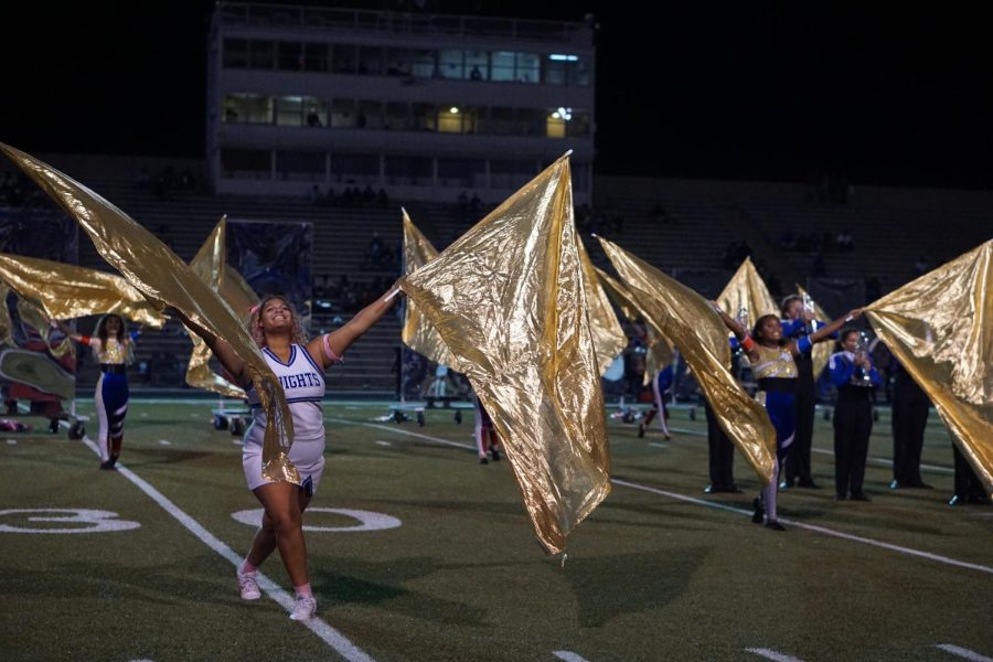 Genesis Ritcherson performs at the McCallum vs. Navarro halftime show with colorguard flags while in her cheerleading uniform. After gaining colorguard experience as a freshman at Anderson, Ritcherson decided to stick with it even after transferring to McCallum and joining the cheer squad. “I have to start preparing the night before and to make sure I have everything I need for the whole day.” Ritcherson said. “Sometimes, I have to bring three pairs of shoes for cheer, color guard and regular school."