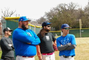 The alumni brain trust of Hudson Stancliff (Class of 2009), Colton Collins (Class of 2009), Travis Russell (Class of 2010) and Sam Russell (Class of 2016) survey their varsity opposition as the latest edition of McCallum Baseball takes the Northwest Park Field for the 2023 Alumni Baseball Game.