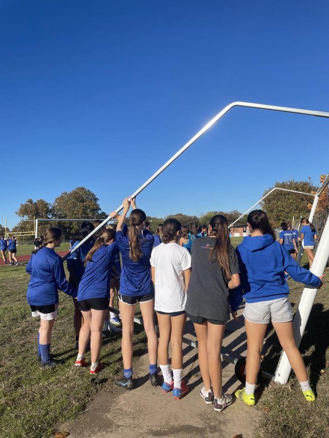 McCallum girls soccer work together to lift soccer goal. Preparing for the new nets McCallum soccer will receive from 4ATX foundation.  